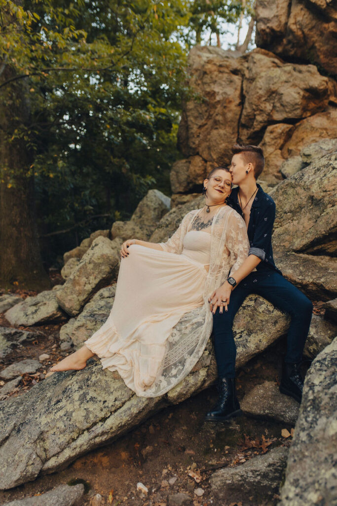 A person leaning back on their partner as they sit on rocks 
