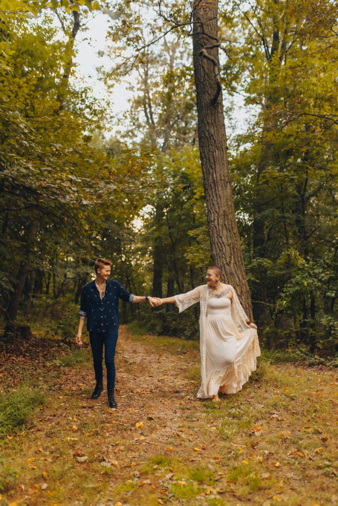 A couple with their hands outstretched holding each other and walking on a trail
