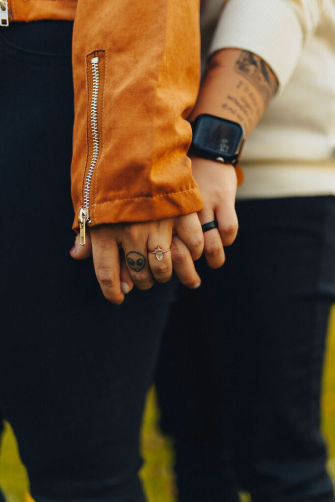 Close up of two hands holding each other showing off engagement rings 