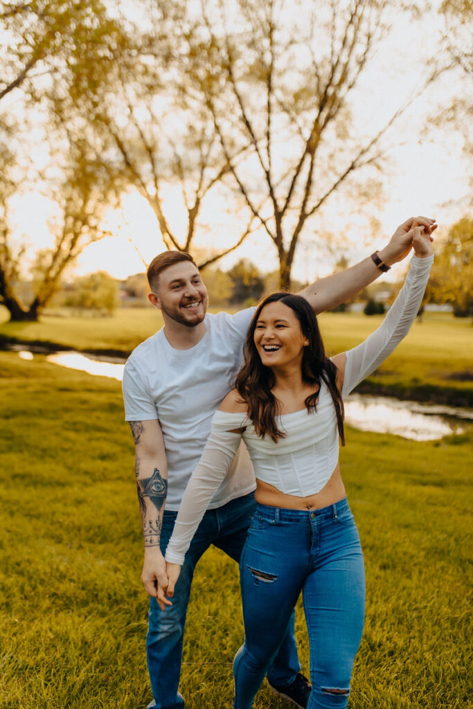 Two people standing in a row with their arms outstretched laughing in a park 