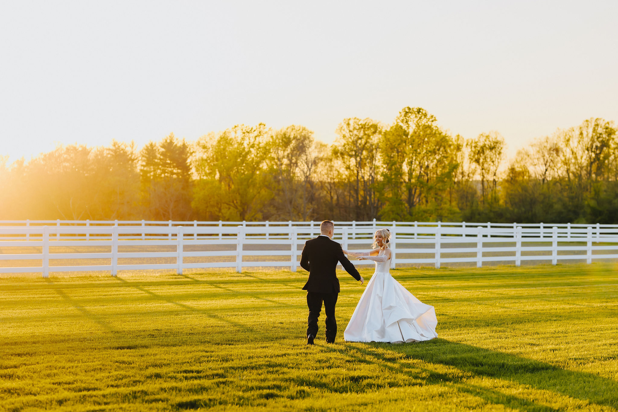 Documentary style wedding photography showing a couple holding hands and walking in a field.