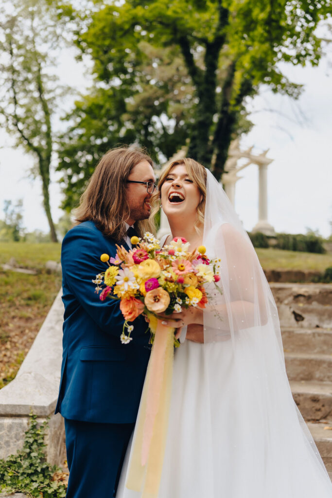 A newlywed couple standing close together and laughing. 