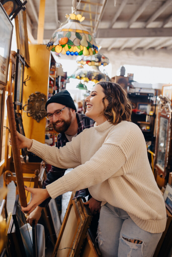 An engaged couple laughing at a picture they are holding up during their engagement session