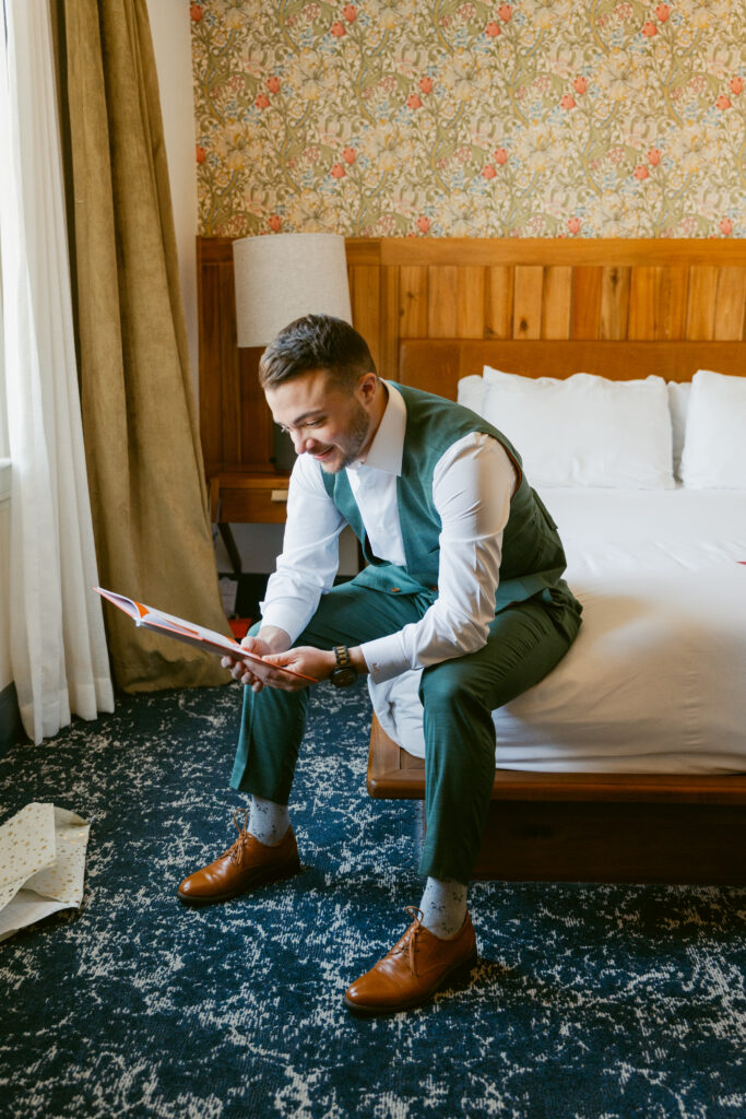 A groom wearing a green suit reading a card from his partner in private