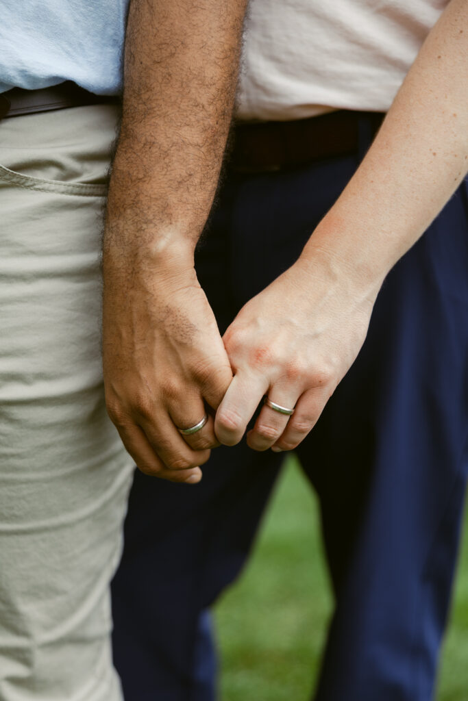 Two men hold hands, showing off their engagement rings 