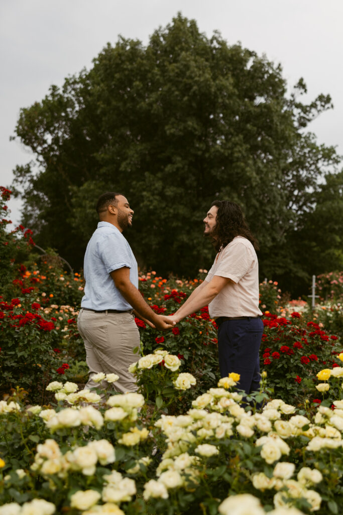 A couple holds hands, standing in front of each other, smiling 
